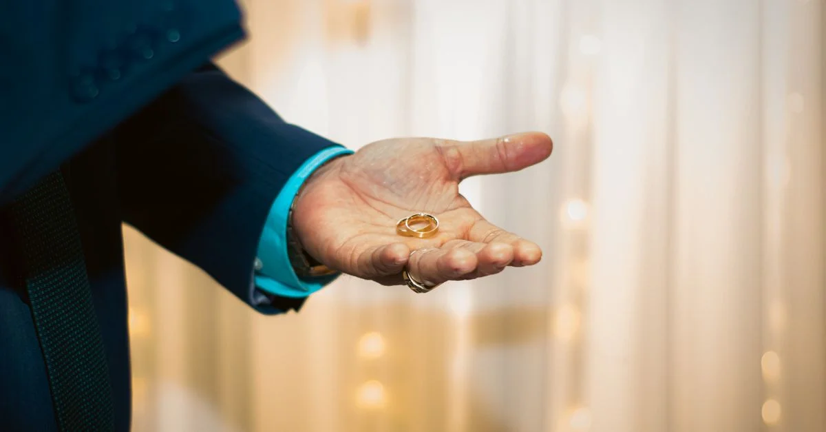 Gros plan sur une main tenant des alliances, symbolisant le mariage et l'engagement.