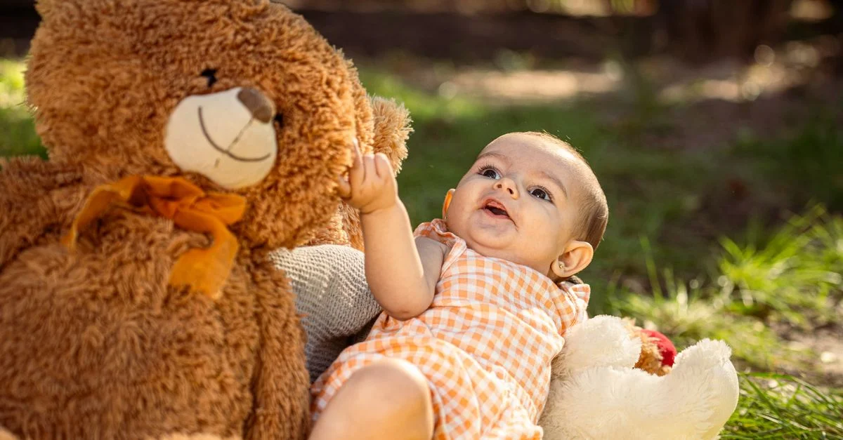 Mignon bébé en combinaison vichy profitant de moments avec des oursons en extérieur.