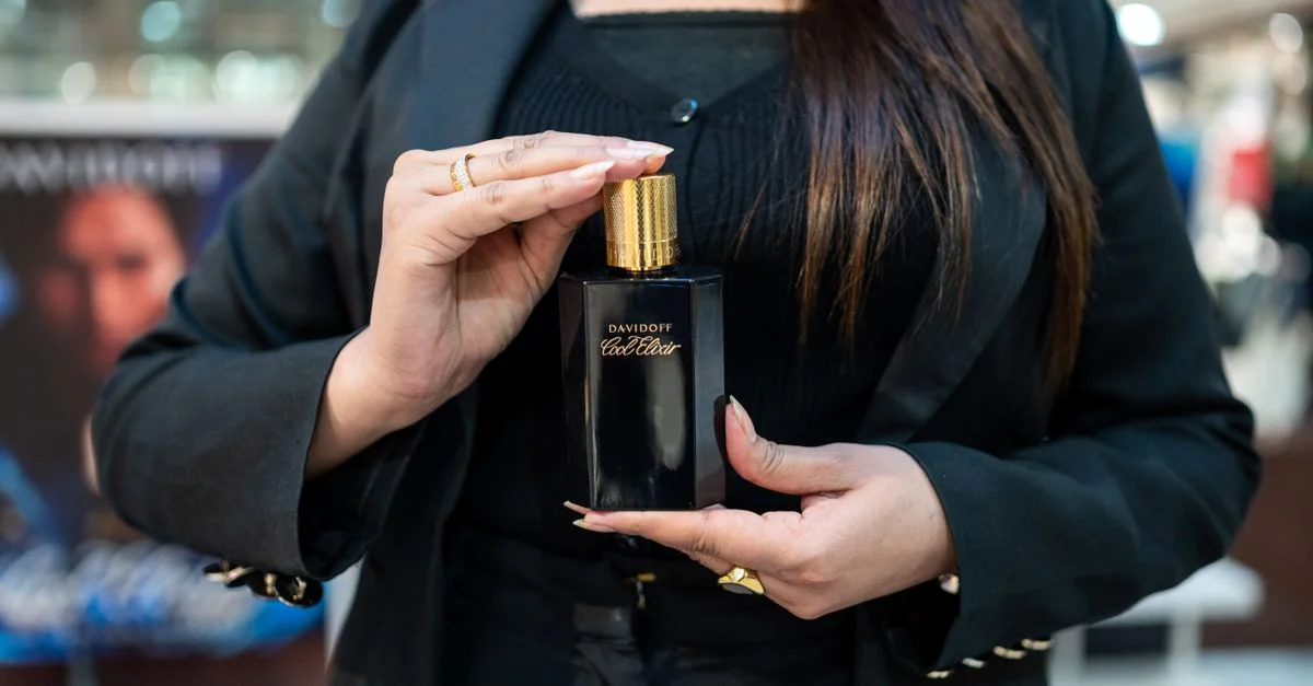 Gros plan sur une femme tenant un flacon de parfum Davidoff Cool Water, illustrant une fragrance de luxe.