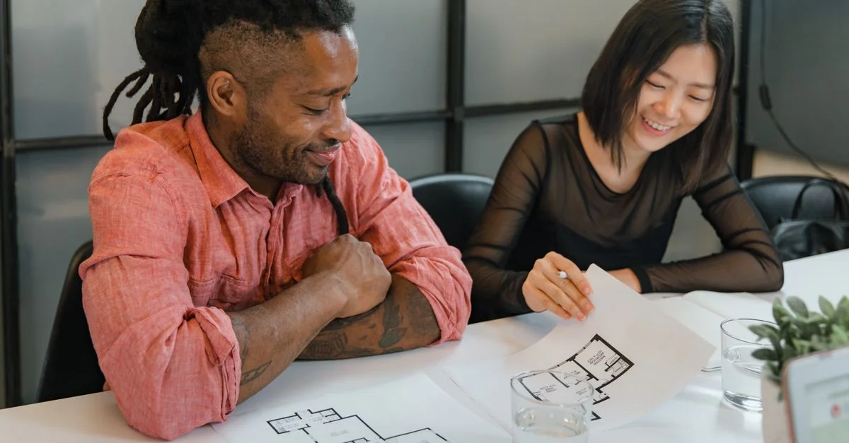 Une équipe diversifiée de professionnels collaborant sur des plans architecturaux, favorisant le travail d'équipe et la créativité.