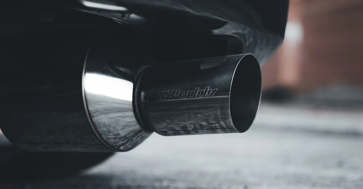 Détail d'une sortie d'échappement de voiture avec condensation, mettant en avant des éléments en chrome et en acier.